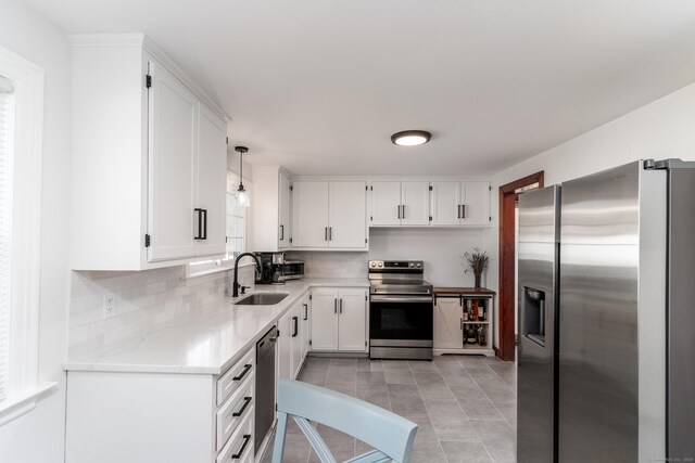 kitchen featuring decorative backsplash, white cabinetry, a sink, appliances with stainless steel finishes, and light tile patterned floors