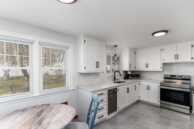 kitchen with stainless steel electric range, a sink, light countertops, white cabinetry, and backsplash