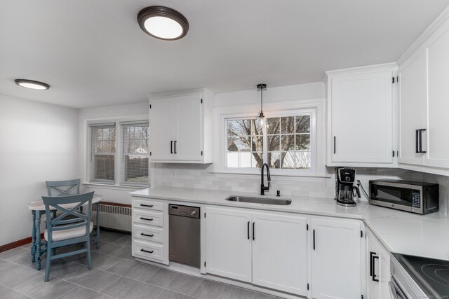 kitchen featuring a sink, decorative backsplash, stainless steel appliances, and white cabinetry