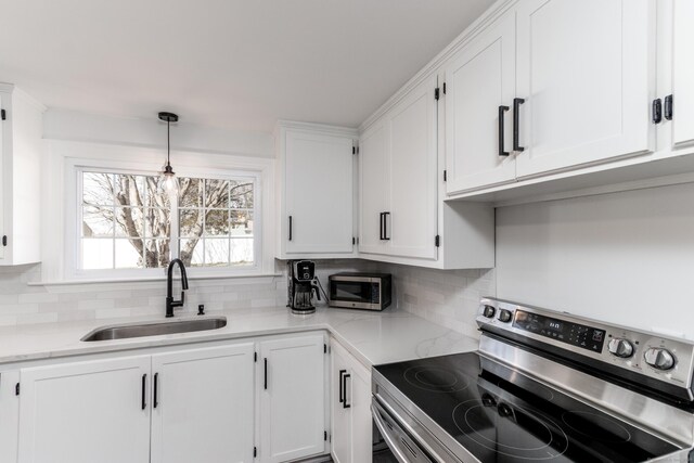 kitchen with a sink, white cabinetry, backsplash, and stainless steel appliances