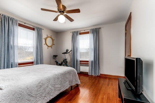 bedroom with dark wood-type flooring, a ceiling fan, and baseboards