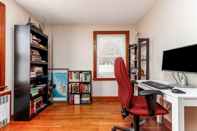 office area featuring baseboards, radiator heating unit, and wood finished floors