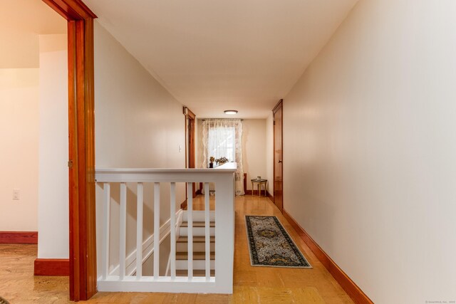 corridor featuring baseboards and light wood-style flooring