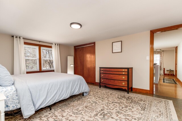 bedroom with baseboards, multiple windows, and a closet