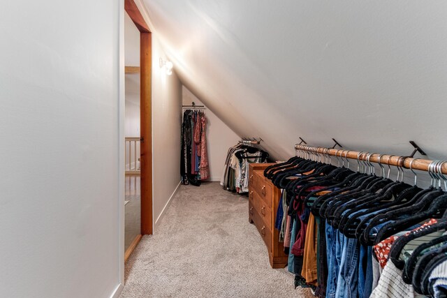 walk in closet featuring vaulted ceiling and light carpet