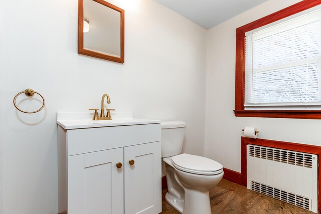 bathroom with toilet, baseboards, radiator heating unit, and vanity