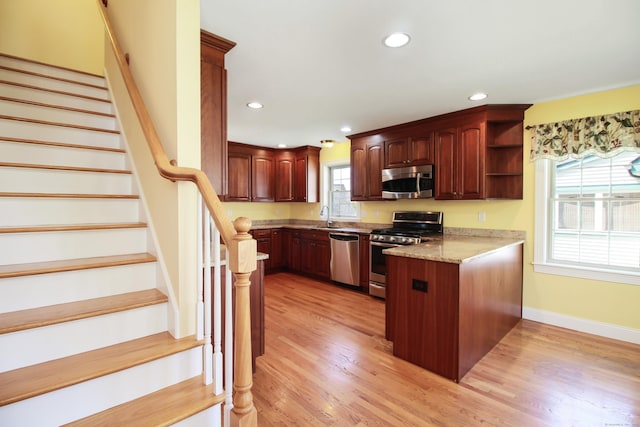5 Marjories Way Unit 5, East Lyme, CT 06357 - kitchen with appliances with stainless steel finishes, a peninsula, a sink, open shelves, and light wood finished floors