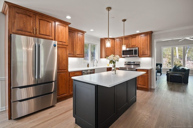 kitchen with brown cabinets, stainless steel appliances, ornamental molding, and light wood-type flooring
