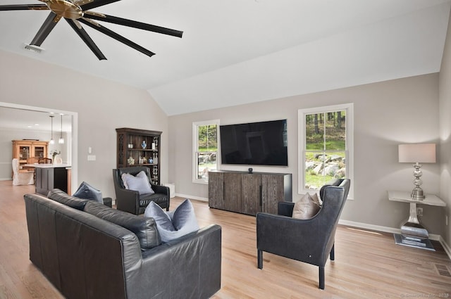living room featuring baseboards, vaulted ceiling, and light wood finished floors