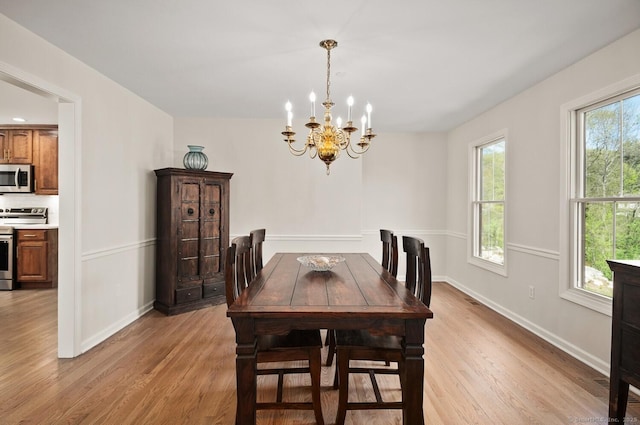dining space featuring an inviting chandelier, light wood-style flooring, and baseboards