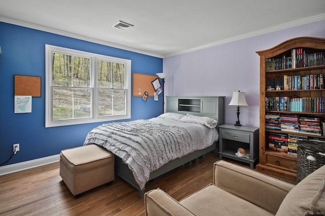 bedroom with baseboards, visible vents, ornamental molding, and wood finished floors