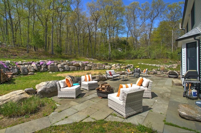 view of patio featuring an outdoor living space with a fire pit and a forest view