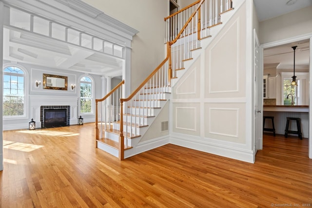 stairs with a decorative wall, a wealth of natural light, wood finished floors, and a brick fireplace