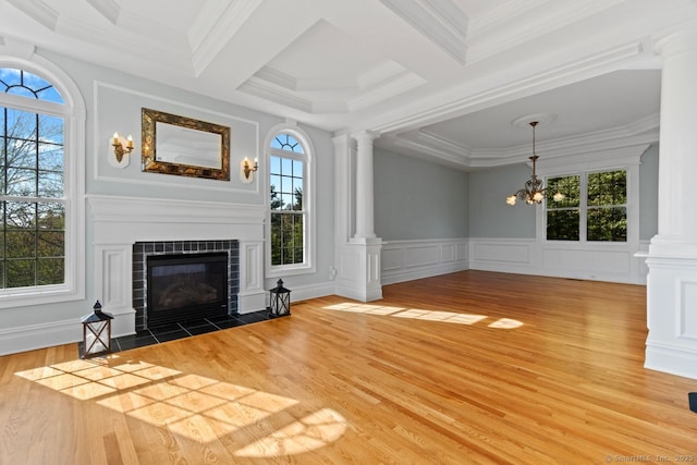 unfurnished living room featuring decorative columns, plenty of natural light, and wood finished floors