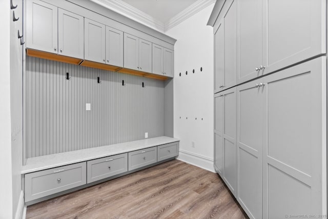 mudroom featuring crown molding, light wood-style flooring, and baseboards