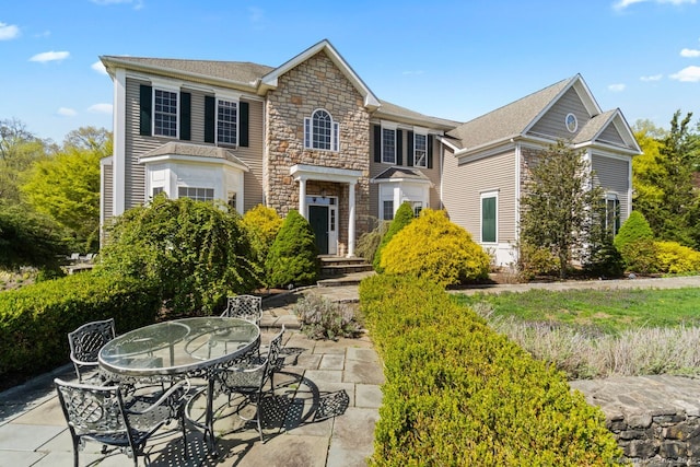 view of front of house with a patio area, outdoor dining area, and stone siding