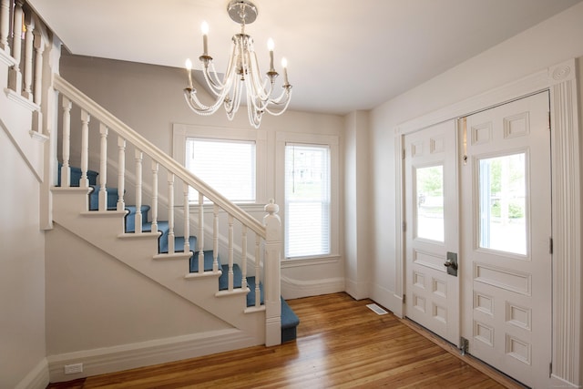 221 Broadway, Norwich, CT 06360 - entryway featuring visible vents, stairs, wood finished floors, baseboards, and a notable chandelier