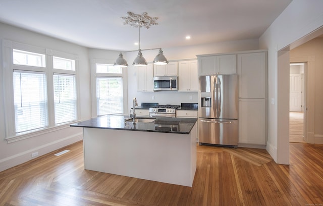 221 Broadway, Norwich, CT 06360 - kitchen with white cabinets, a sink, a kitchen island with sink, stainless steel appliances, and baseboards