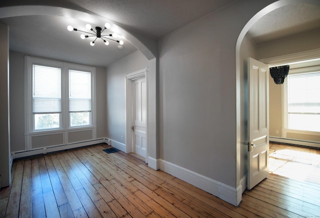 221 Broadway, Norwich, CT 06360 - interior space featuring arched walkways, a baseboard radiator, a baseboard heating unit, a chandelier, and hardwood / wood-style floors