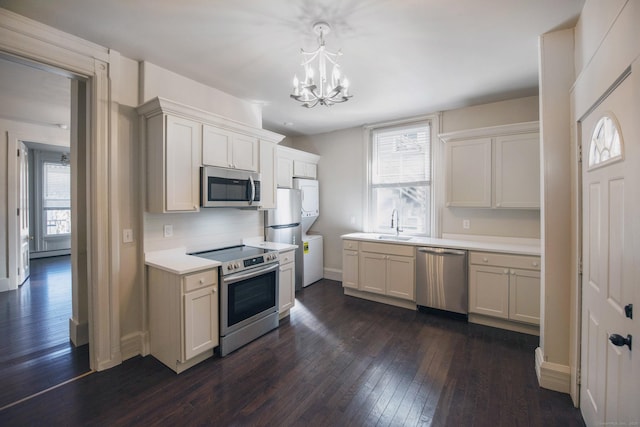 221 Broadway, Norwich, CT 06360 - kitchen with stacked washer / dryer, appliances with stainless steel finishes, light countertops, an inviting chandelier, and dark wood-type flooring