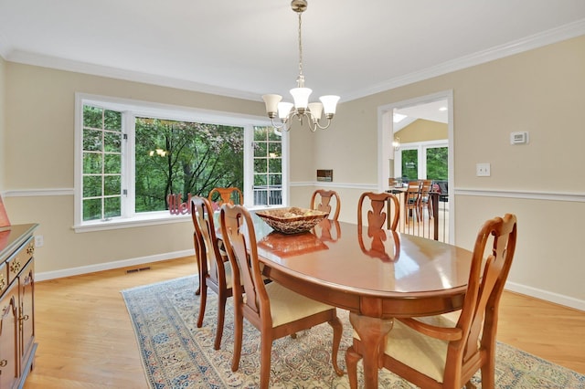 dining room with a chandelier, ornamental molding, light wood-style floors, and baseboards