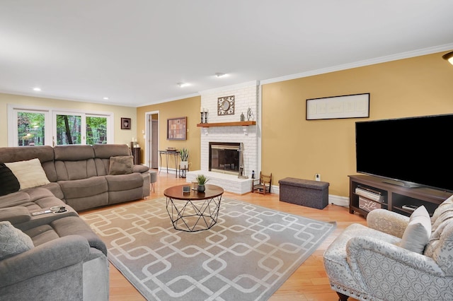 living room featuring crown molding, wood finished floors, a brick fireplace, baseboards, and recessed lighting