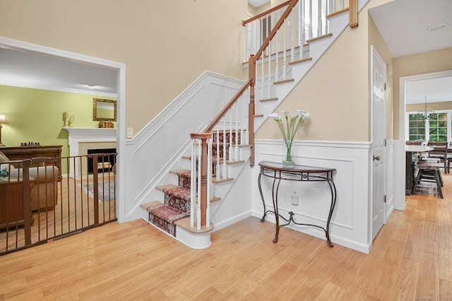 stairway with wood finished floors, a fireplace, a decorative wall, and wainscoting