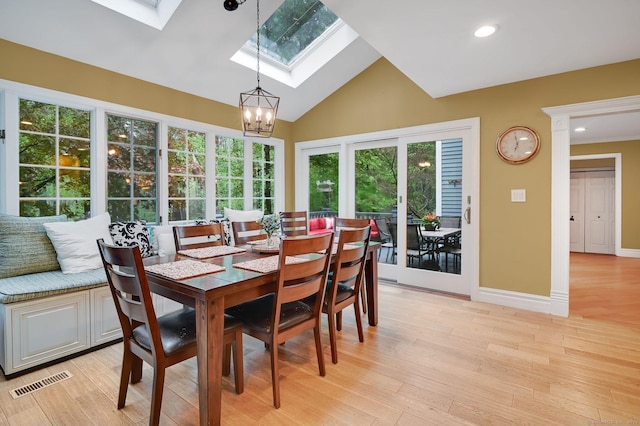 dining room with a skylight, a chandelier, light wood finished floors, baseboards, and recessed lighting