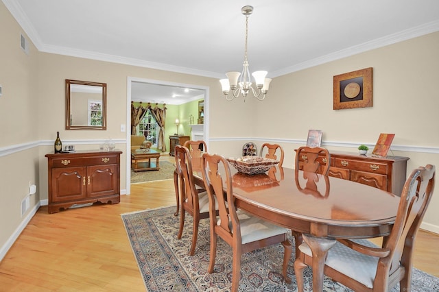 dining area with light wood-type flooring, a chandelier, and crown molding