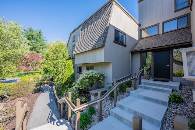 exterior space featuring entry steps and a shingled roof