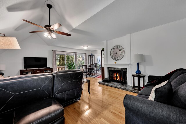 living area with ceiling fan, wood finished floors, vaulted ceiling, and a fireplace
