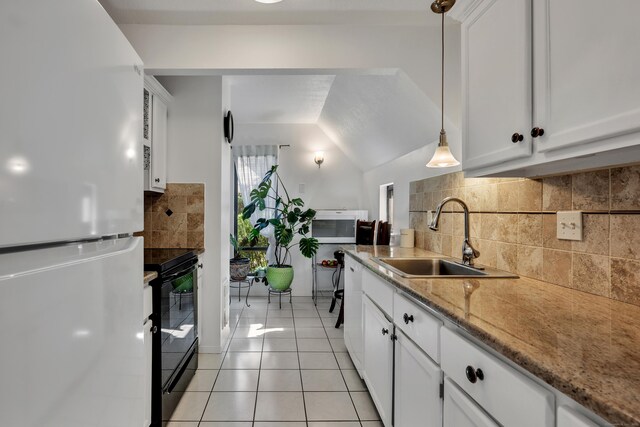 kitchen featuring a sink, black electric range, freestanding refrigerator, light tile patterned floors, and tasteful backsplash