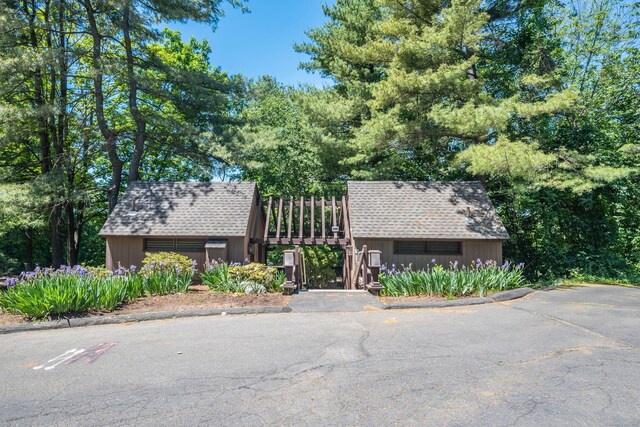 view of front of property with roof with shingles, a storage unit, an outbuilding, and fence