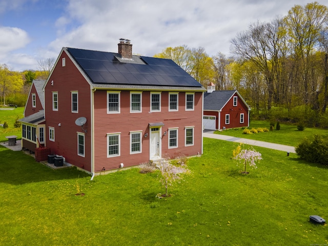 rear view of property with a lawn, an outbuilding, a chimney, and central AC unit