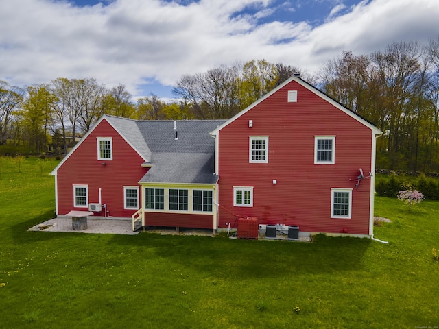 back of house with a yard, central AC, a shingled roof, and a patio area