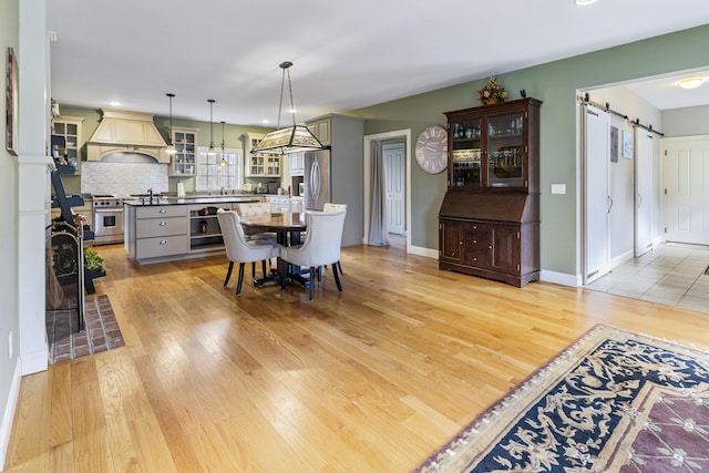 dining room featuring baseboards, light wood-type flooring, and a barn door