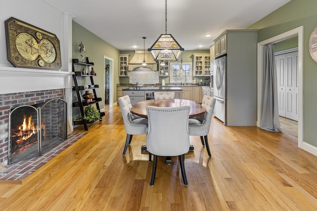 dining area with a brick fireplace, recessed lighting, baseboards, and light wood finished floors
