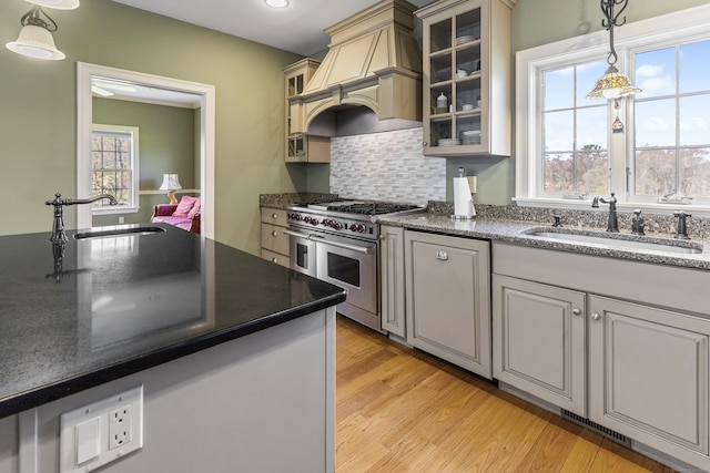 kitchen with range with two ovens, pendant lighting, a sink, and custom range hood