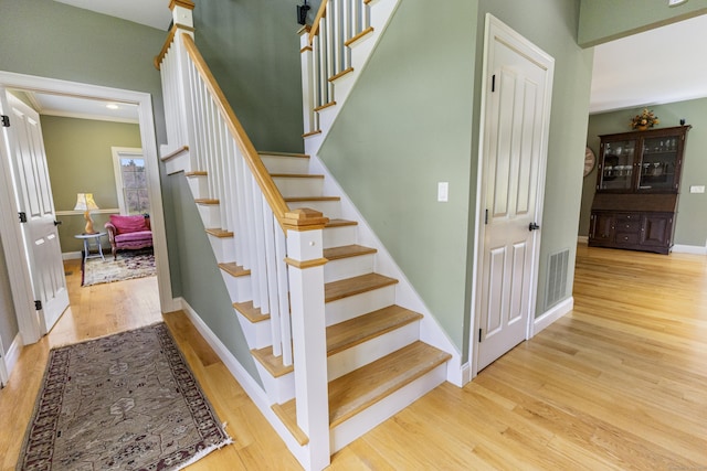 stairway with baseboards, wood finished floors, and visible vents