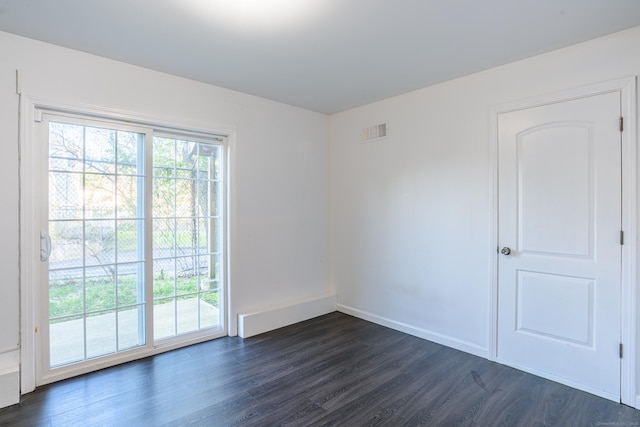 empty room featuring visible vents, baseboards, and dark wood-style floors