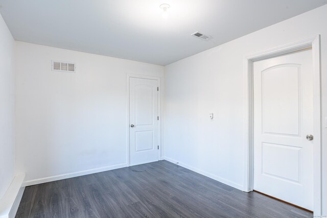 spare room with baseboards, dark wood-style floors, and visible vents