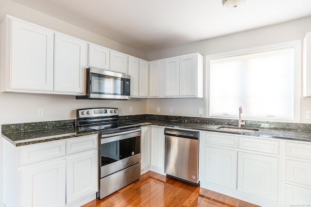 kitchen featuring a sink, dark stone counters, white cabinets, and stainless steel appliances