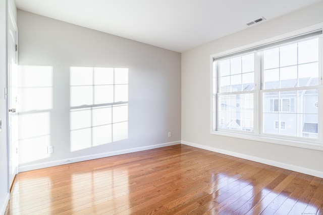 empty room featuring baseboards, hardwood / wood-style floors, and visible vents