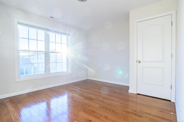 spare room featuring baseboards, wood finished floors, and visible vents