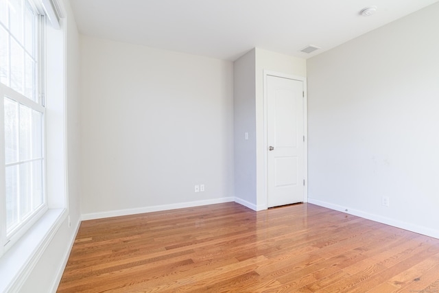 spare room featuring light wood-style floors, baseboards, and visible vents