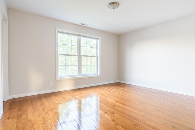 spare room with baseboards, light wood-style flooring, and visible vents