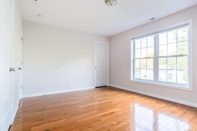 empty room featuring baseboards, light wood-style flooring, and visible vents