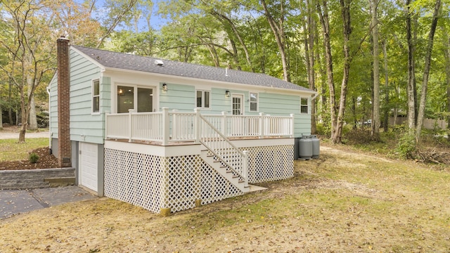 rear view of property with a garage, a deck, a chimney, stairs, and driveway