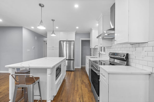 kitchen with a kitchen island, baseboards, wall chimney range hood, a sink, and stainless steel appliances