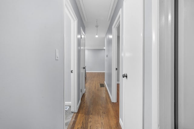 corridor with baseboards, wood finished floors, and attic access